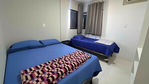 Ein Hotelzimmer mit zwei Betten, einem Fenster mit Vorhängen, einer Klimaanlage und einem Nachttisch.
