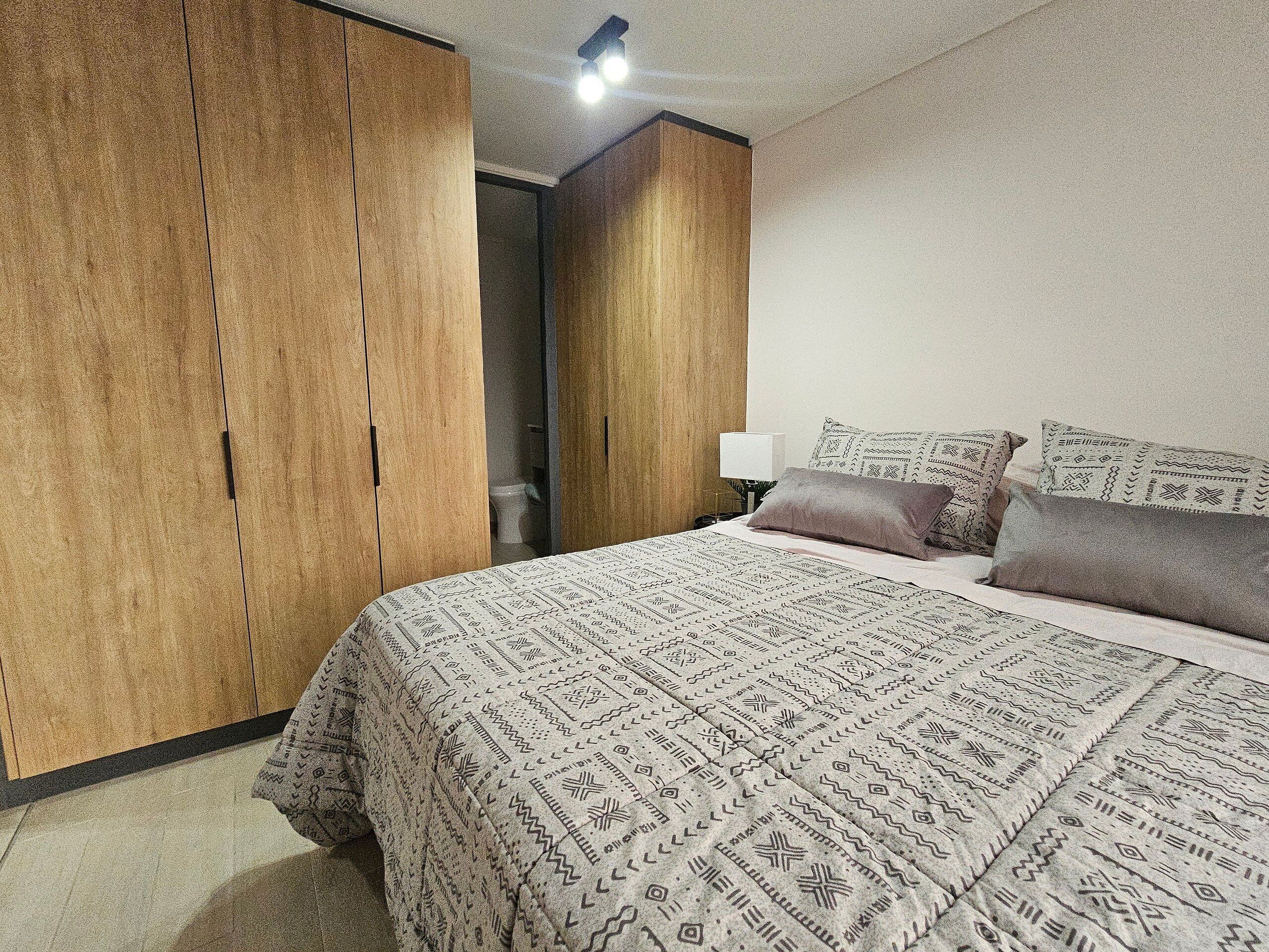 Une chambre à coucher avec un grand lit, une literie à motifs, une armoire et une table de chevet avec une lampe.