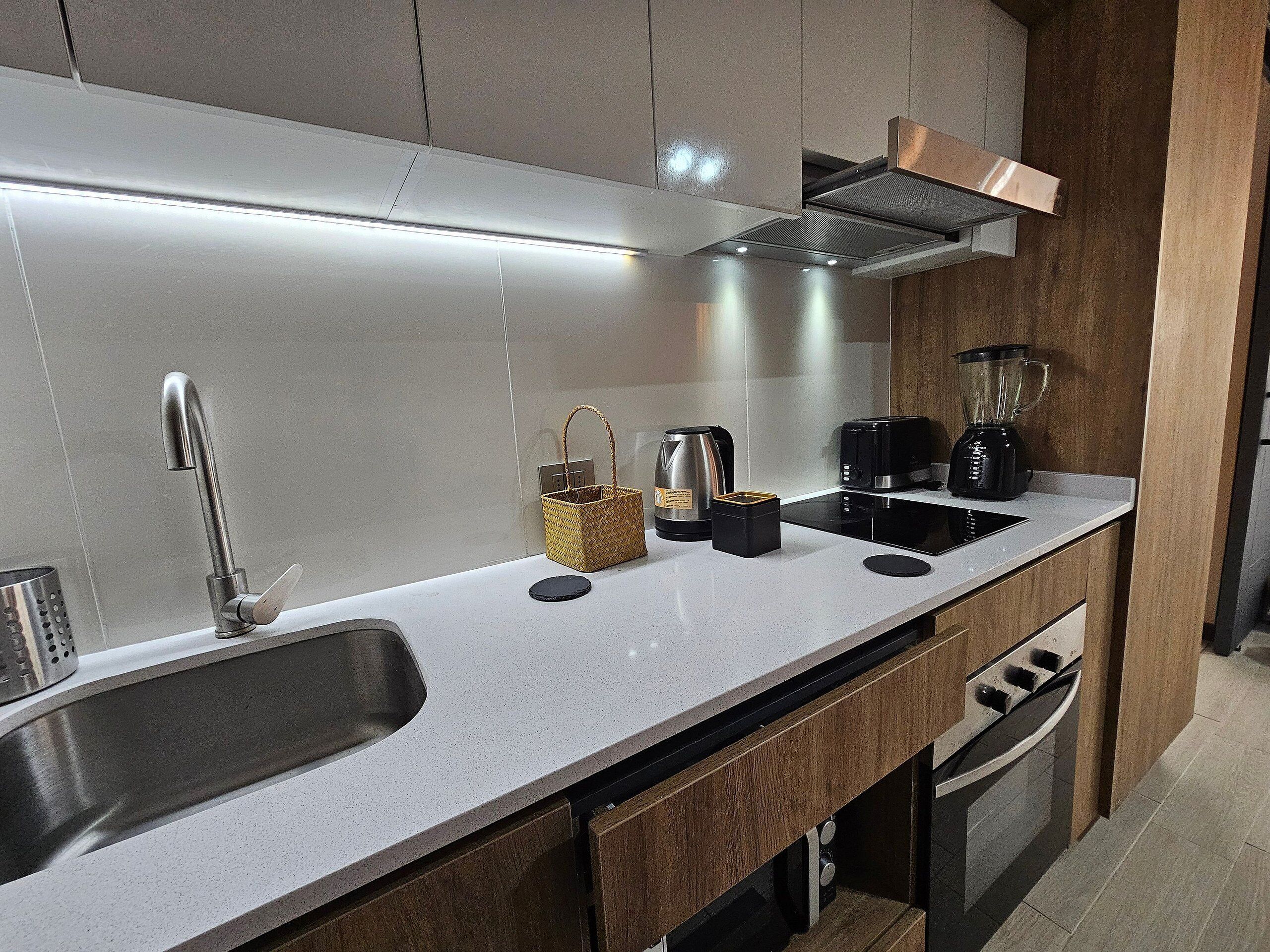 A modern kitchen with a stainless steel sink, a built-in stove, and a black coffee maker.