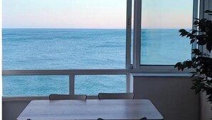 A room with a large window overlooking the sea, a wooden table, and two chairs. - Front line beach Benalmádena La Perla Playa Paraíso (BENALMÁDENA)