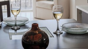 A dining table with two wine glasses and a vase, set against a city view through large windows. - BT Homes - Mar del Plata, Av. Colon (Mar del Plata)