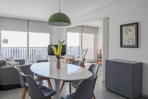 Un salon moderne avec une table à manger ronde, des canapés gris et une suspension verte.