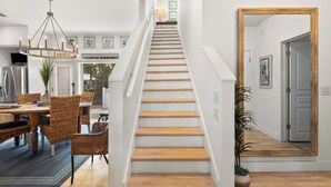 A staircase with wooden steps leading to a second floor, flanked by white walls and a wooden-framed mirror. - Charming Beach Cottage, 2 Pools and Tennis Access + Free Attraction Tickets! (Santa Rosa Beach)