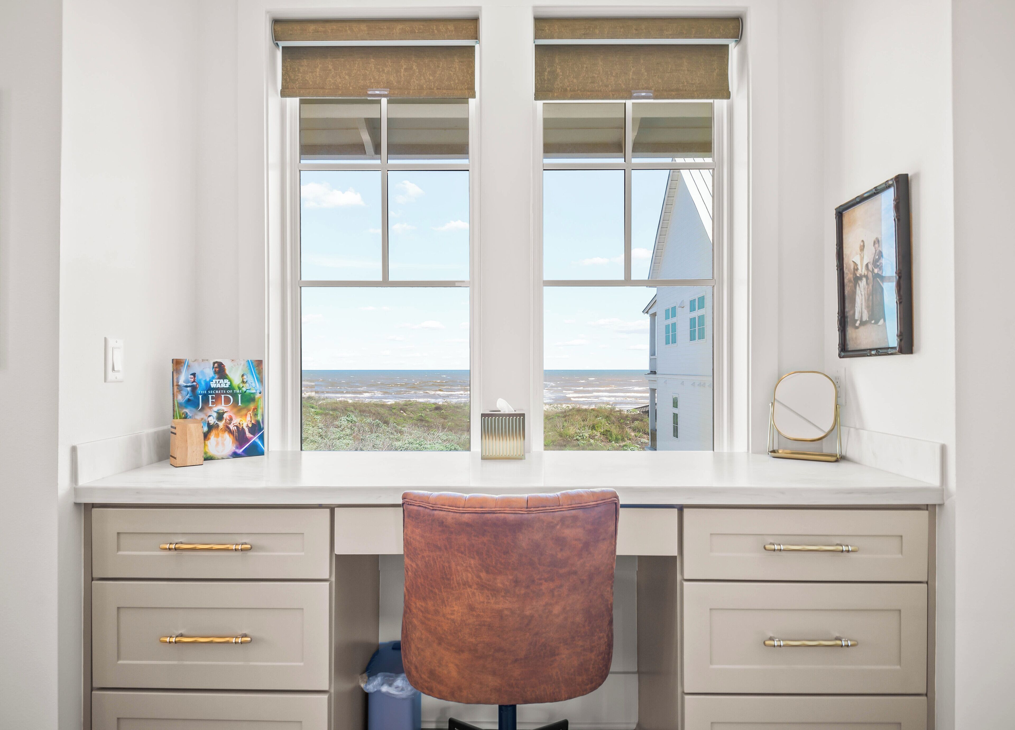 A room with a desk, two windows with blinds, a chair, and a radiator.