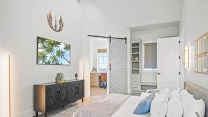 A bedroom with a bed, a dresser, a sliding closet door, and a framed picture on the wall. - 160 COA Dune Or Do Not (Port Aransas)