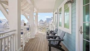 A covered porch with wooden railings and a bench, overlooking a residential area. - 160 COA Dune Or Do Not (Port Aransas)