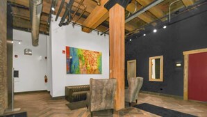 An art gallery with a large abstract painting, wooden beams, and a red door. - River North Rooftop With In and Out Parking 3 (Chicago)