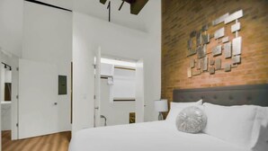A hotel room with a bed, a brick wall, and a white door. - River North Rooftop With In and Out Parking 3 (Chicago)