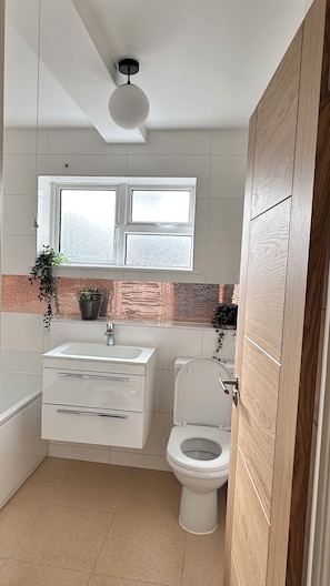 Ein Badezimmer mit einem weißen Waschbecken, einer Toilette und einem Fenster über dem Waschbecken.