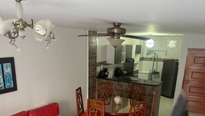 A living room with a red sofa, a dining table with chairs, a ceiling fan, and a kitchen area in the background. - Private apartment 🍃 with sea view 🥳🌇🌊 edf el morro (Santa Marta)