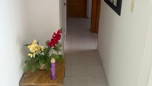 A narrow hallway with a wooden door at the end, a small table with a vase of flowers, and a framed picture on the wall. - Private apartment 🍃 with sea view 🥳🌇🌊 edf el morro (Santa Marta)