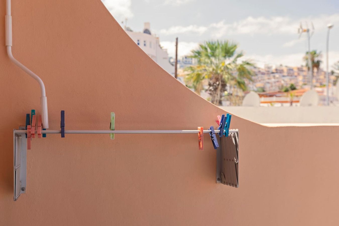 A metal rack with clothes hanging on it, attached to a wall with a curved design.