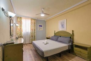 A bedroom with a bed, bedside tables, a ceiling fan, and a window with curtains.