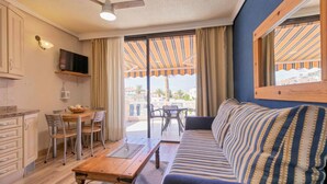 Un salon confortable avec un canapé et une table à manger, un ventilateur de plafond et une vue sur le balcon extérieur.