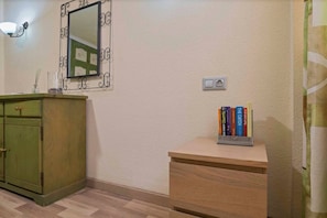 A room with a green cabinet, a small wooden desk, a mirror with decorative frame, and a wall-mounted light fixture. - Condo in Costa Adeje · ★4.75 · 1 bedroom · 1 bed · 1 bath (Costa Adeje)