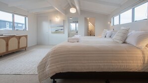 A spacious bedroom with a large bed, a wooden cabinet, and a view of the outside through a window. - Absolute Lakefront | Panoramic Views & Spacious Stay for 10 (Rotorua)