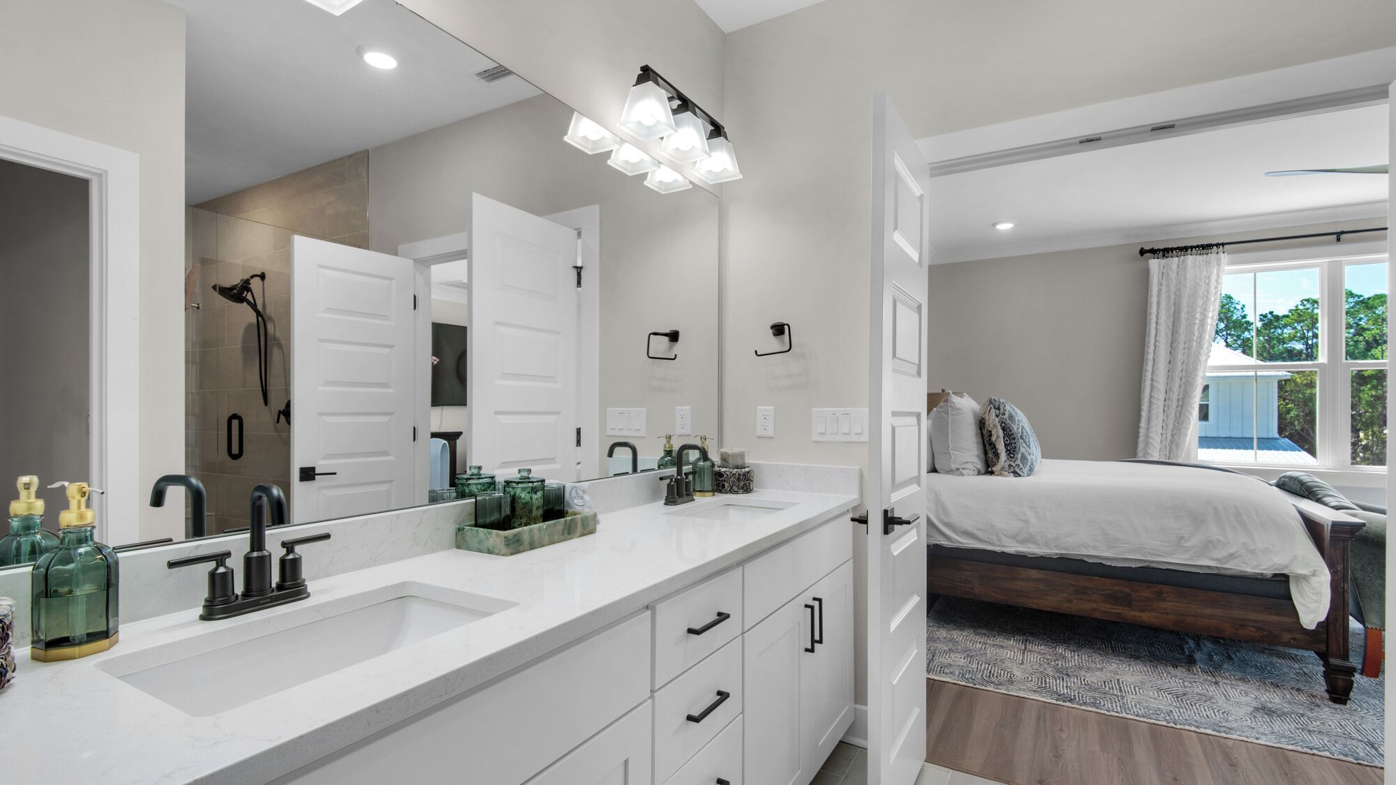A modern bathroom with a large mirror, dual sinks, and a shower.