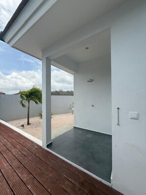 Ein moderner, offener Wohnbereich mit einer Holterrasse, einer kleinen Palme und Blick zum Himmel.