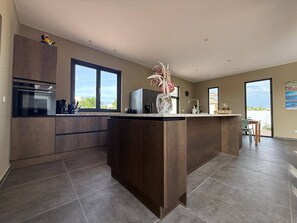 A modern kitchen with a central island, built-in appliances, and large windows. - Villa Milamor Curacao - Harmonie, Grote Berg (Grote Berg)