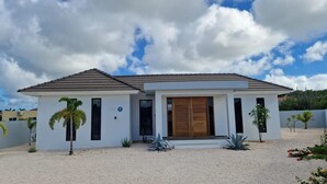 Ein modernes, zweistöckiges Haus mit Flachdach, Holztür und Auffahrt mit Kies.