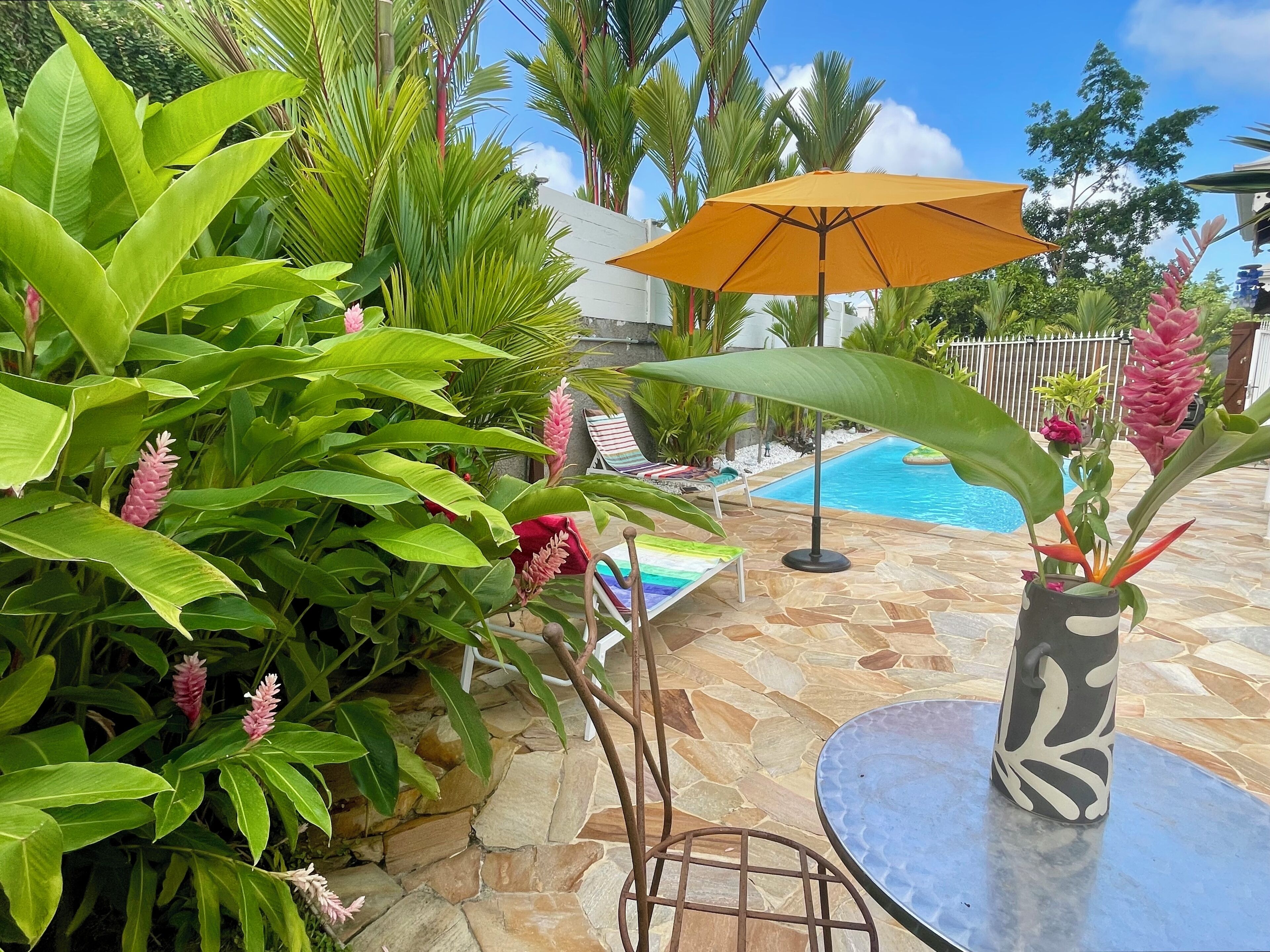 A poolside area with a stone patio, a round table, and a lounge chair.