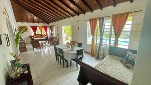Une pièce spacieuse avec un plafond haut, un coin repas avec une table ronde et des chaises, un canapé et un lit recouvert d’une courtepointe matelassée.