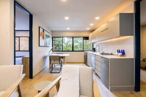 A modern kitchen with a dining area, large windows, and a view of greenery outside. - Digital Nomad Paradise ~1BR unit in Manila’s Heart (Medellín)