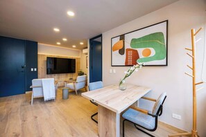 A modern kitchen with a dining area, wooden flooring, and a large abstract painting on the wall. - Digital Nomad Paradise ~1BR unit in Manila’s Heart (Medellín)