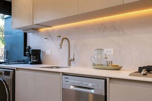A modern kitchen with a dishwasher, a coffee maker, and a glass pitcher on the counter.