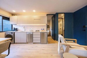 A modern kitchen with white cabinets, stainless steel appliances, and a wooden dining table with chairs. - Digital Nomad Paradise ~1BR unit in Manila’s Heart (Medellín)