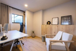 A modern office space with a white desk, a computer, a chair, a small potted plant, and framed artwork on the wall. - Digital Nomad Paradise ~1BR unit in Manila’s Heart (Medellín)