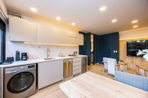 A modern kitchen with a washing machine, dishwasher, and a dining area with a table and chairs. - Digital Nomad Paradise ~1BR unit in Manila’s Heart (Medellín)