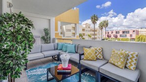 A modern outdoor seating area with a sofa, cushions, a coffee table, and a plant. - FALESIA MARINA APARTMENT (Vilamoura)