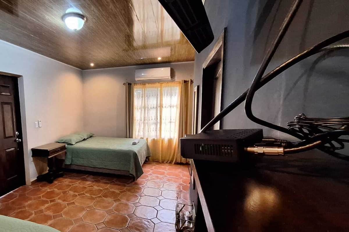 Ein Schlafzimmer mit einem Bett, einem Schreibtisch und einer Klimaanlage.