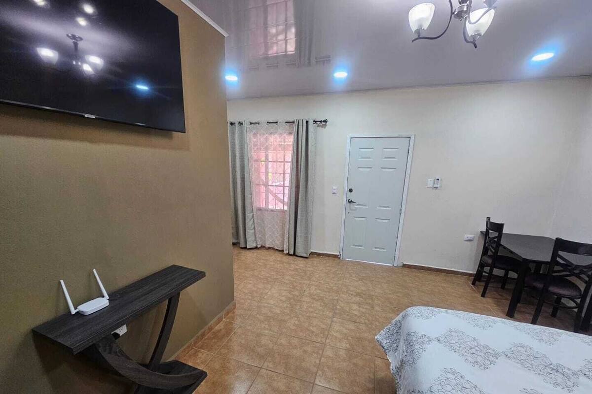 Ein Hotelzimmer mit einem Bett, einem Schreibtisch, einem Stuhl, einem an der Wand befestigten Fernseher und einer Tür.