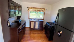 Une cuisine de taille réduite, dotée de meubles de rangement en bois, d’une cuisinière et d’un réfrigérateur.