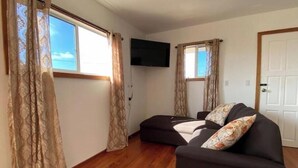 Une pièce avec un canapé, des rideaux à motifs, un téléviseur à écran plat et un plancher en bois.