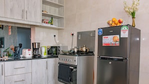 Uma cozinha equipada com fogão, forno e geladeira, além de diversos eletrodomésticos e utensílios.