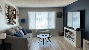 A living room with a sofa, a table, a TV, and a bookshelf. - Highland Estates Condotel (Mesquite)