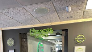 A cafe entrance with a neon sign, a security camera, and a sign indicating the cafe is open. - Highland Estates Condotel (Mesquite)