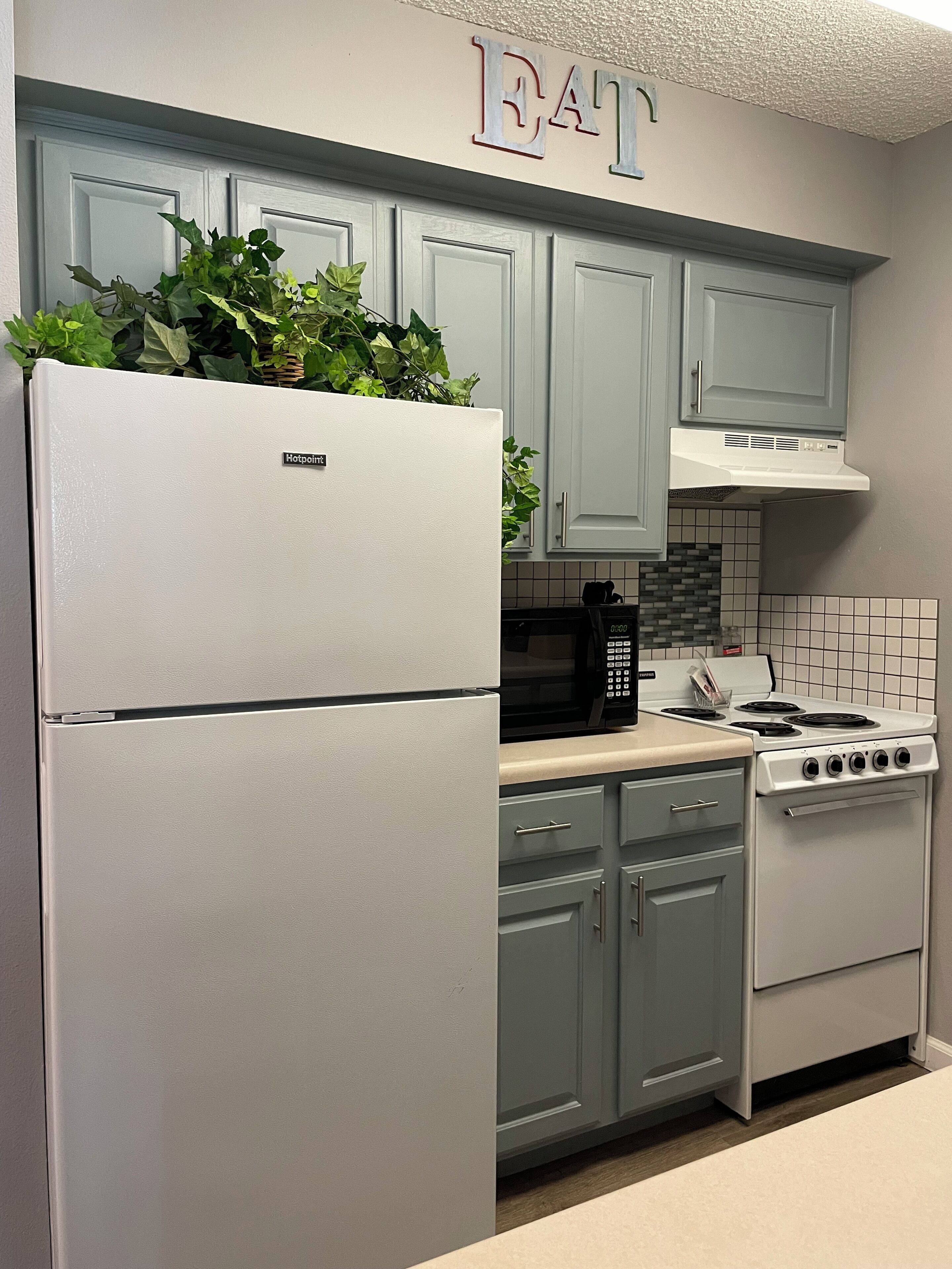 Una cocina con refrigerador, estufa, armarios y un letrero sobre los armarios.
