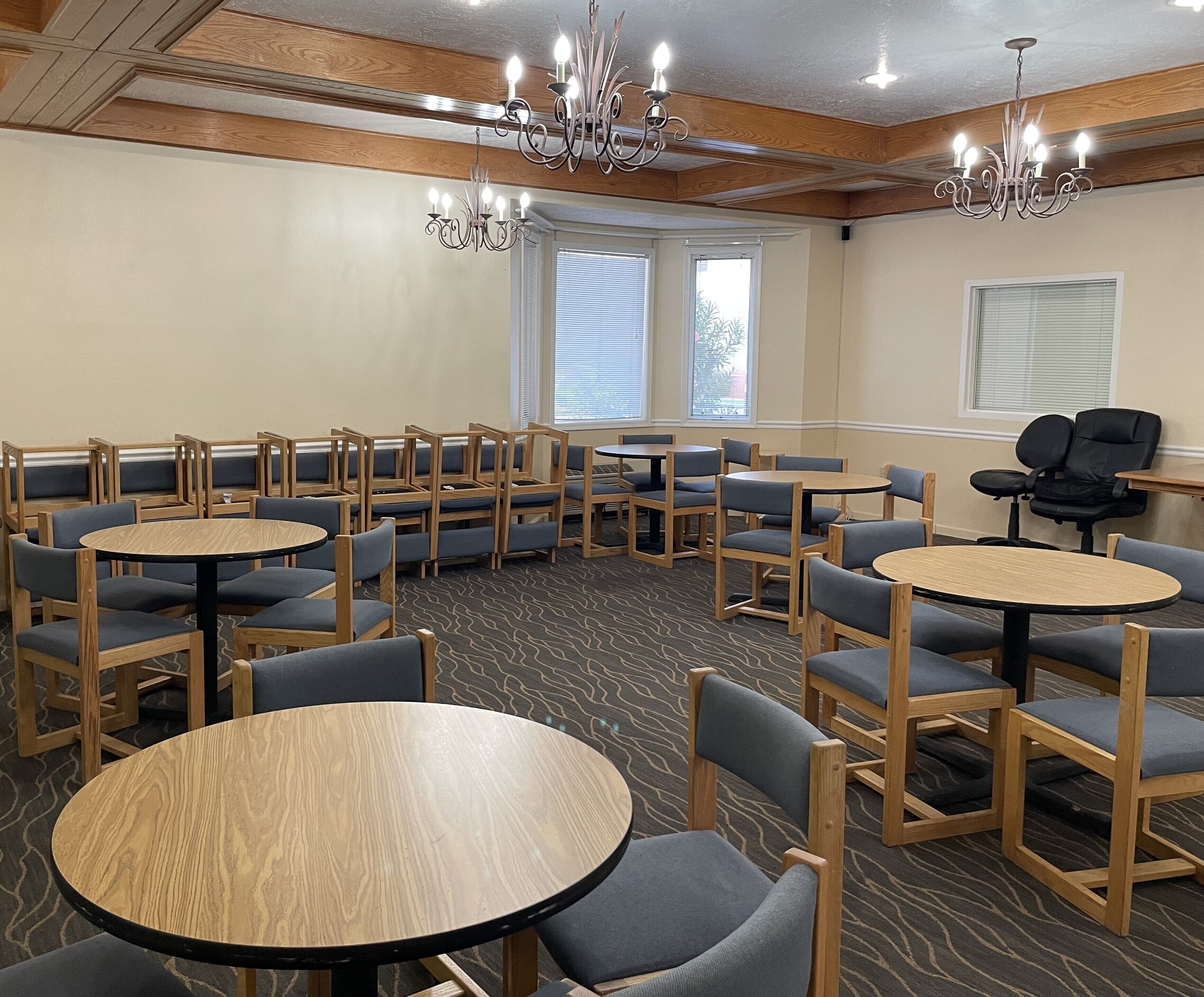 A conference room with round tables and chairs, wooden paneling, and chandeliers.