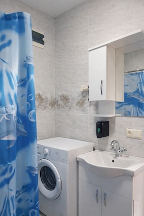 A modern bathroom with a washing machine, a sink, and a mirror.