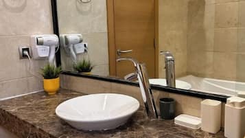 A bathroom with a marble sink, a mirror, a towel rack, a shower area, and a door.