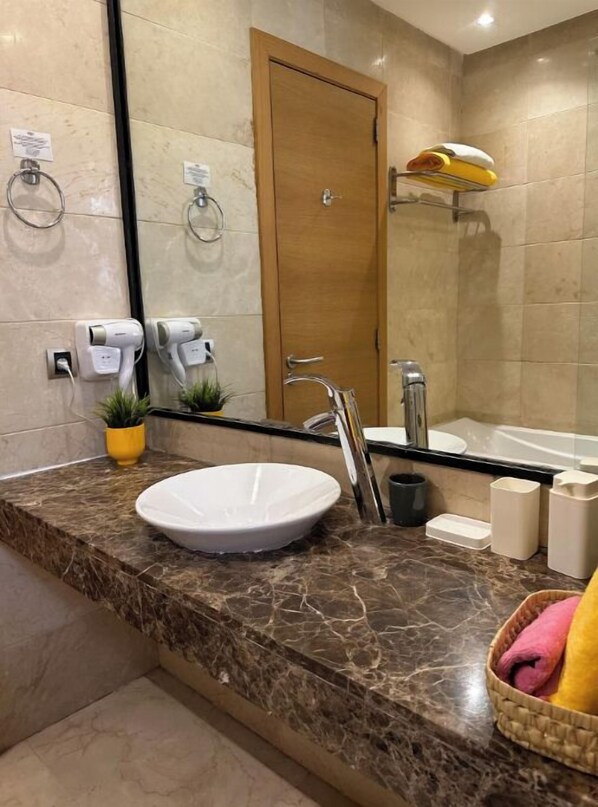 A bathroom with a marble sink, a mirror, a towel rack, a shower area, and a door. - High-end apartment (Ouahat Sidi Brahim)