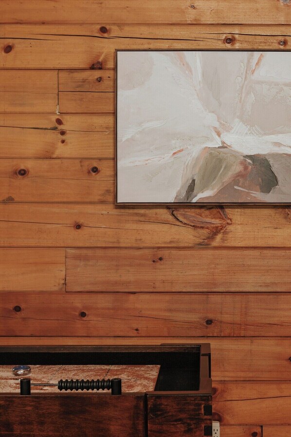 A wooden wall with a framed abstract painting and a black metal object on a textured surface.