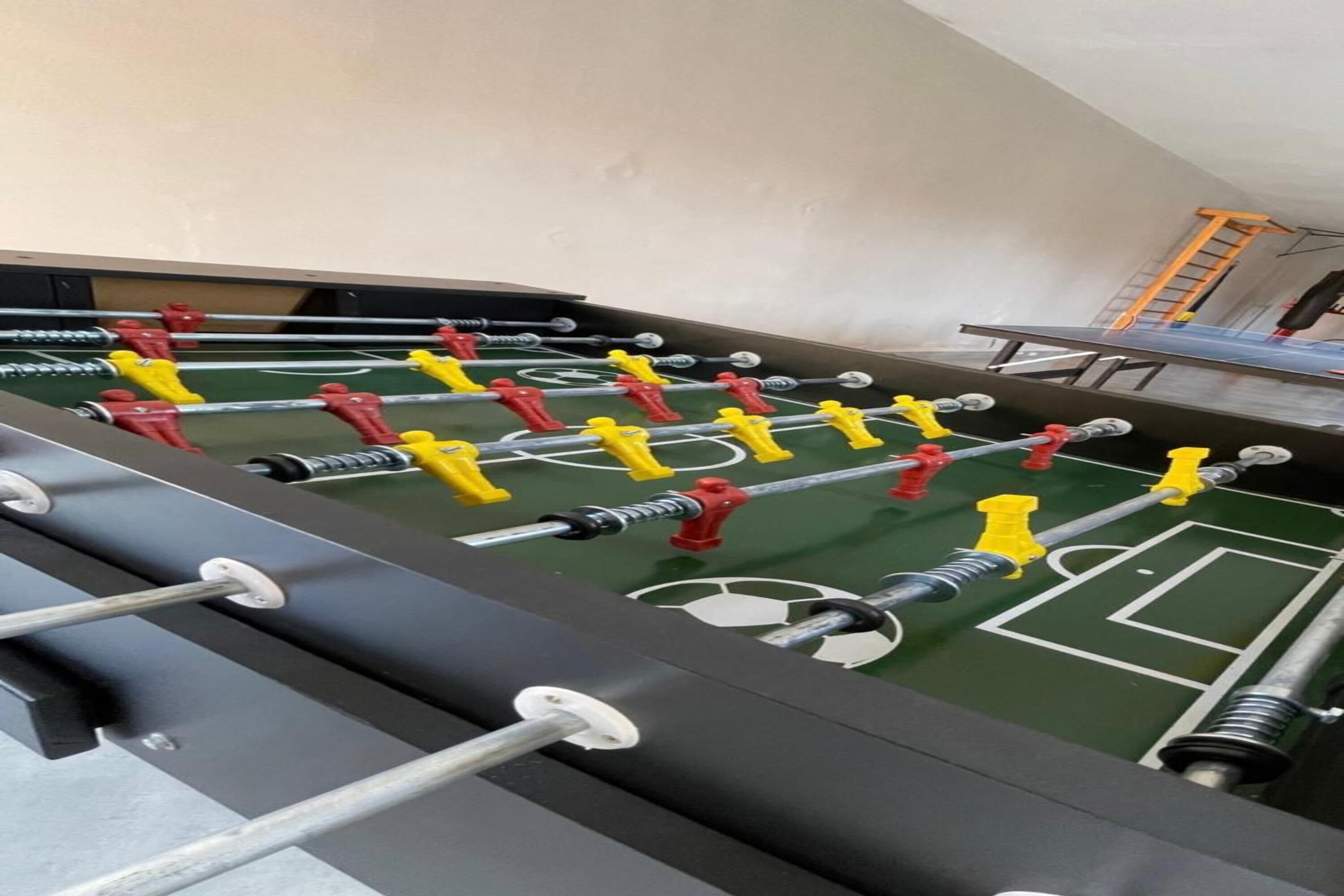 A foosball table with multiple players and a ladder in the background.