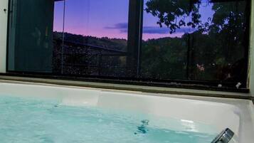 Uma banheira de hidromassagem com vista para o pôr do sol e árvores.