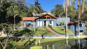 A two-story house with a red roof, surrounded by a well-maintained lawn and a small pond. - Pousada Recanto da Cascata (Aguas de Lindoia)
