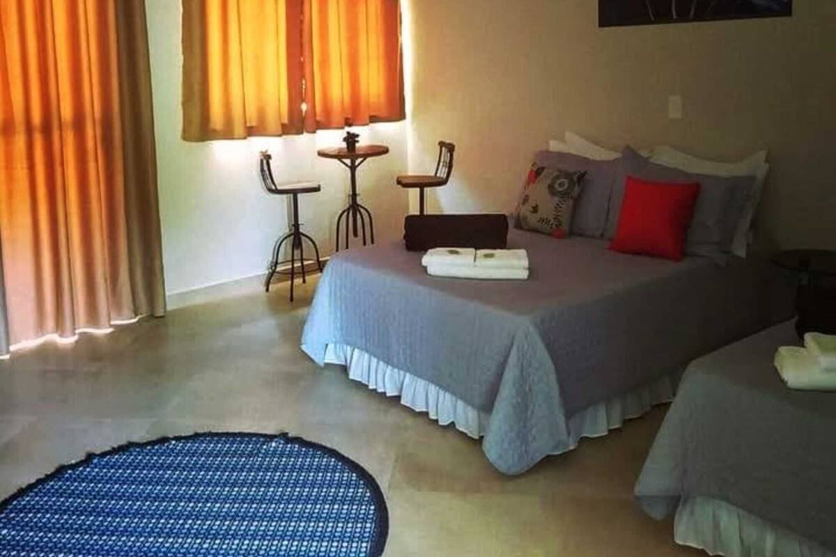 Un dormitorio con una cama, dos sillas, una mesita y un ventilador de techo.
